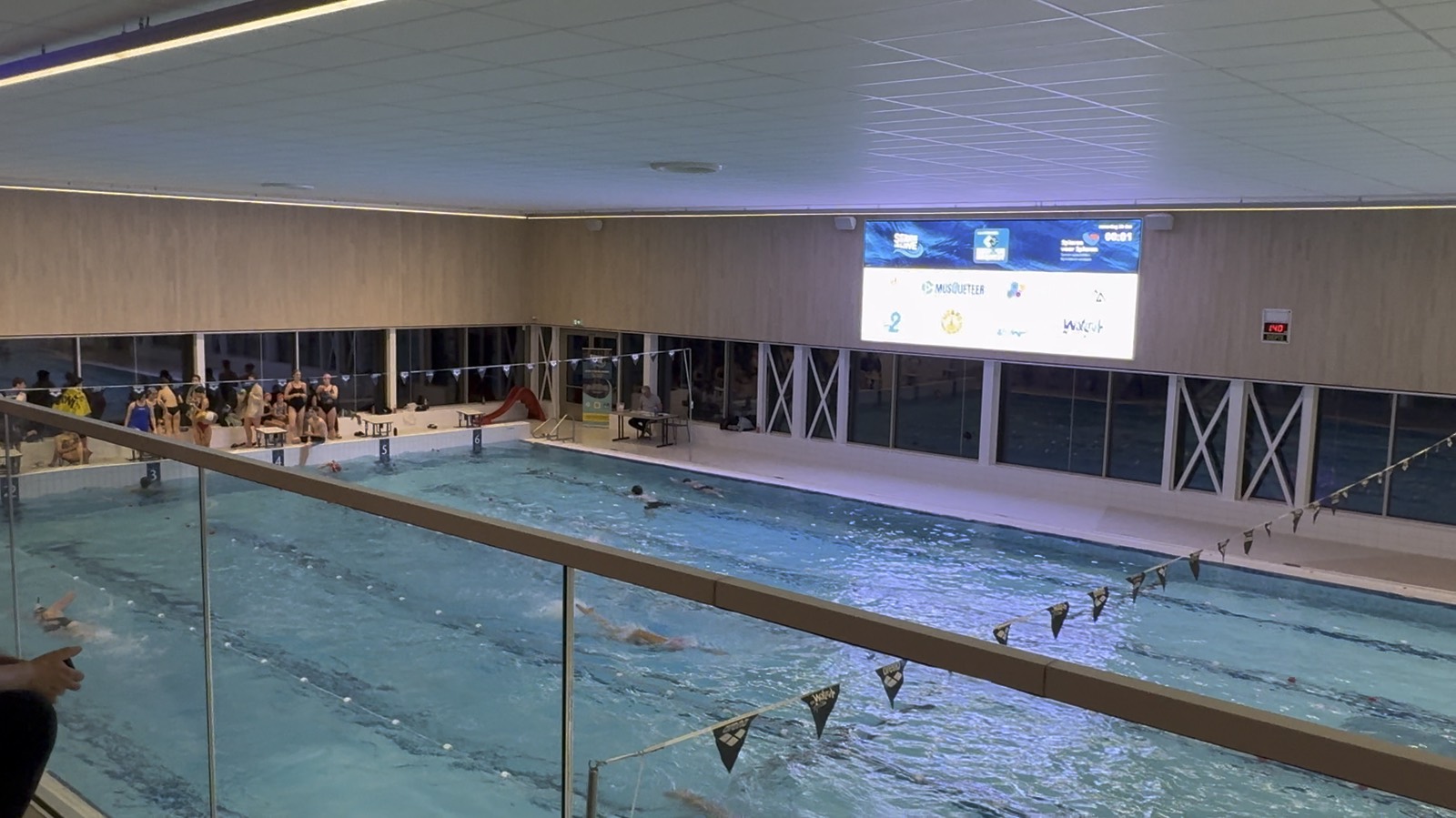 Het scherm in het zwembad met de logo's van de sponsors